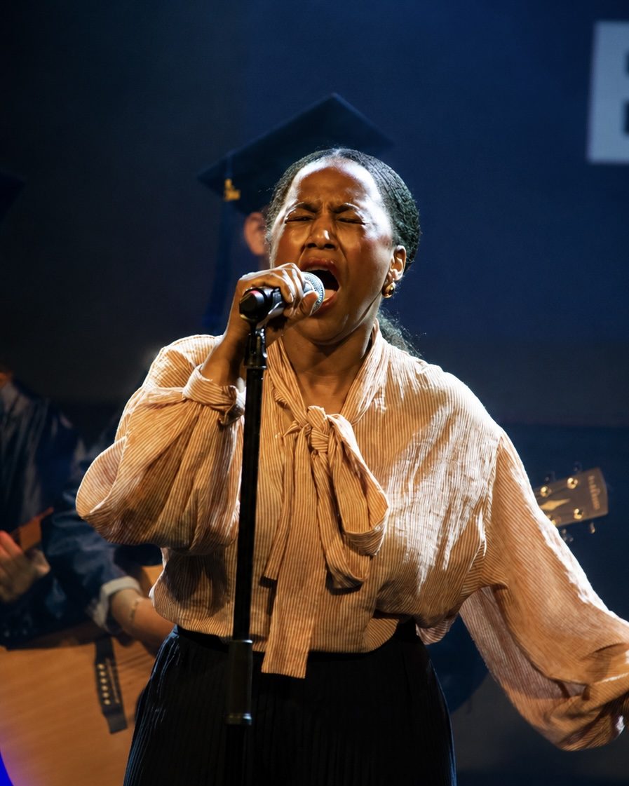 Sångerska i ljus blus sjunger i mikrofon på scen under en livekonsert